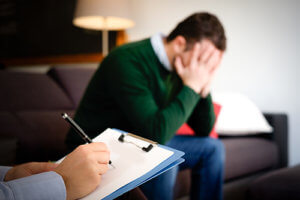 Man on sofa with hands to face at a Florida mens detox center